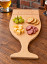 Beukenhouten borrelplank van DecoSpace in de vorm van een speciaalbierglas, met ingefreesd ‘Cheers!’, kaas, worst, druiven en crackers, met speciaalbier op de achtergrond.