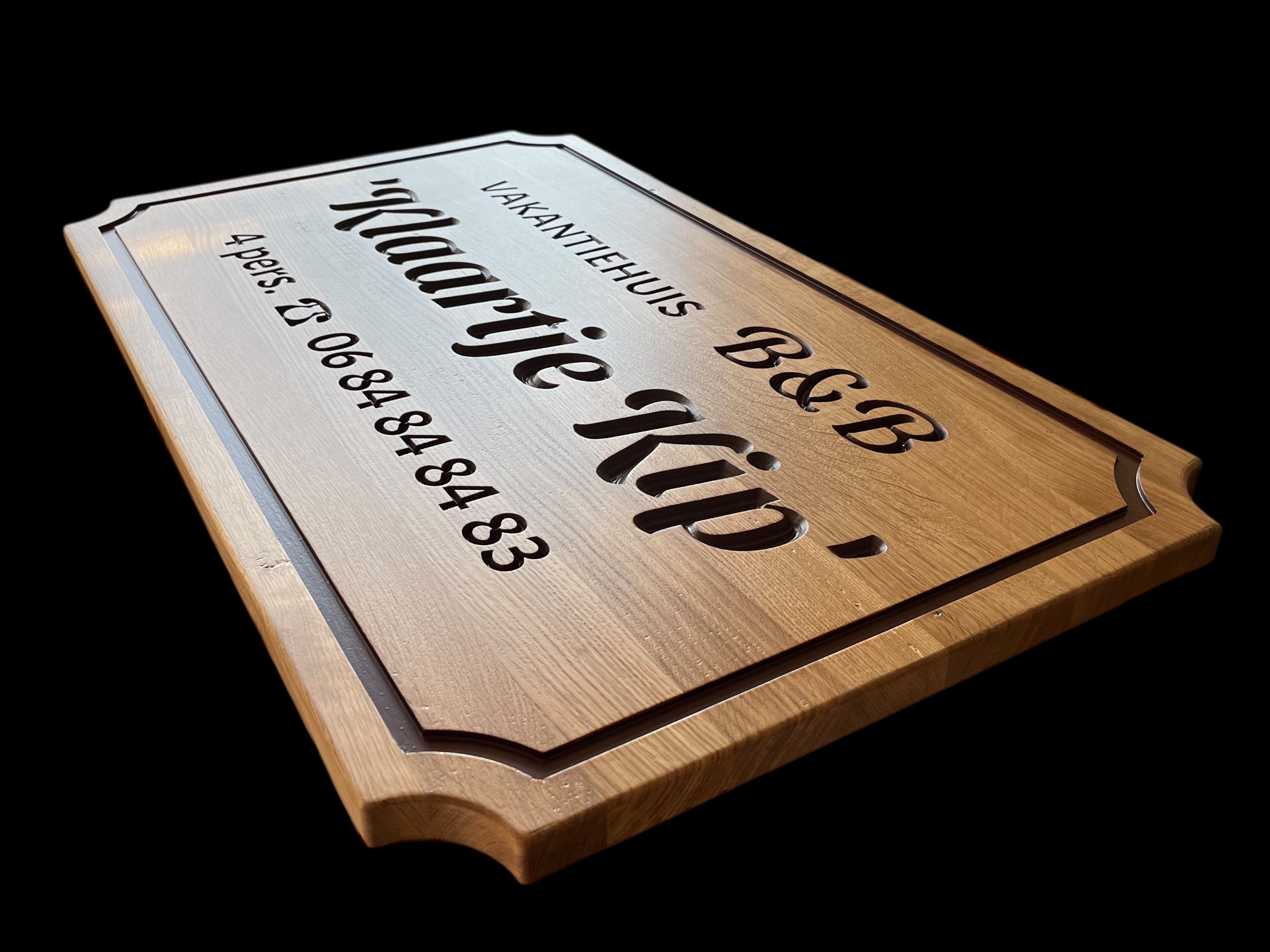 Detail van ingefreesde tekst in massieve houten B&B plank