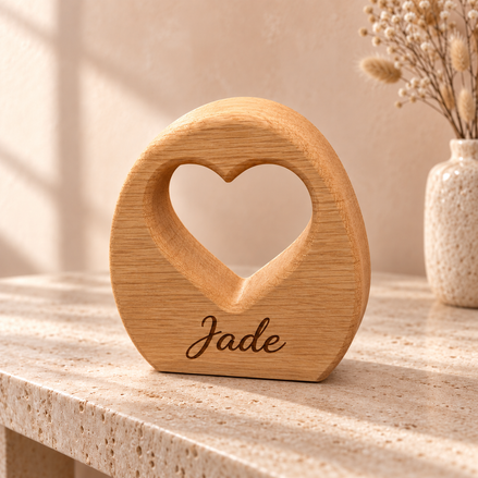 Eiken hartboog van DecoSpace met de naam Jade gegraveerd, op een lichte tafel tegen een warme achtergrond.