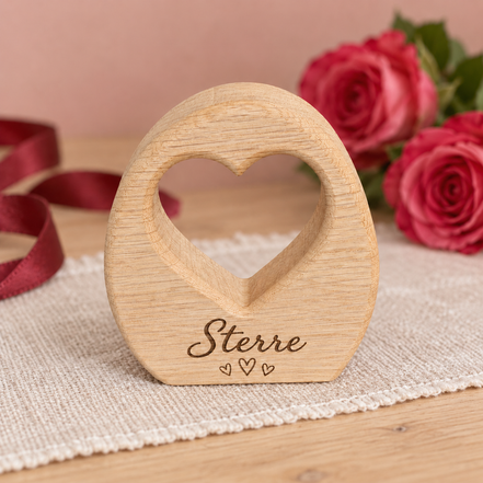 Eiken decoratie van DecoSpace met hartvormige uitsparing, de naam Sterre en drie kleine gegraveerde hartjes, op licht linnen met roze rozen en een rood lint.