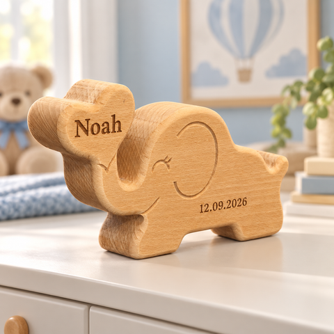 Houten olifant van massief beukenhout met de naam Noah in het hartje en een geboortedatum op het lichaam, op een wit kastje in een babykamer – DecoSpace.