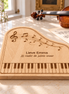Beukenhouten pianoborrelplank van DecoSpace met pianotoetsen, muzieknoten en de gravure ‘Lieve Emma – Jij raakt de juiste snaar’, met een viool en bladmuziek op de achtergrond.